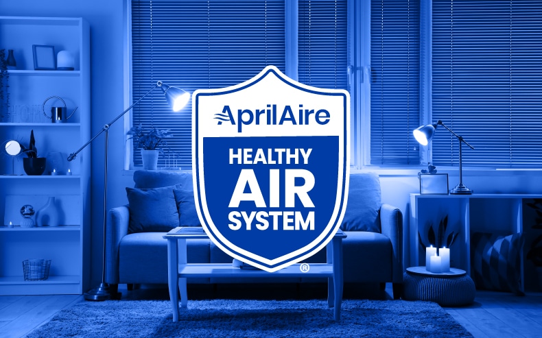 The AprilAire Healthy Air System logo is centered over a blue-toned image of a modern, cozy living room.