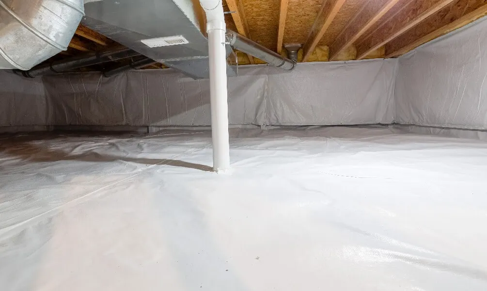 A clean crawl space fully lined with a white vapor barrier covering the floor and walls around support pipes.