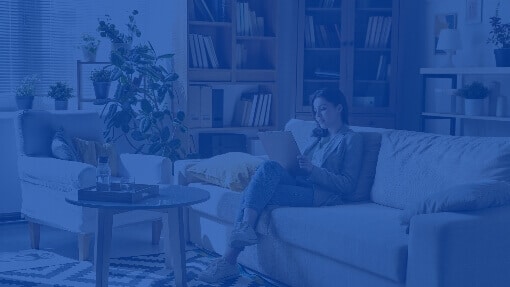 Young woman sitting on a sofa in a home living room, concentrating on work on her laptop computer.